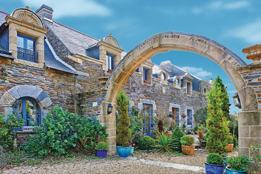 a stone house with an archway in a yard at Le Clos Saint Fiacre in Carentoir