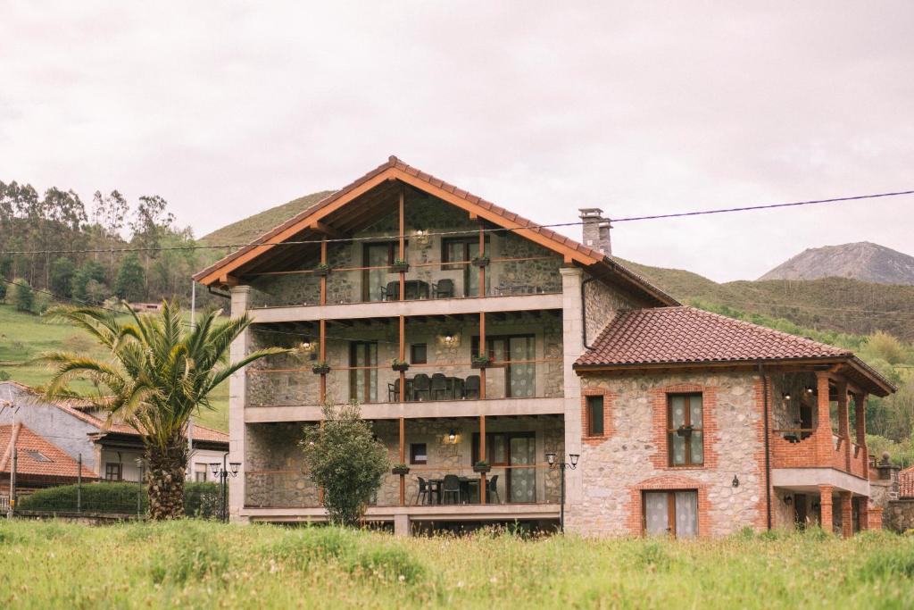 una casa vieja con una palmera delante de ella en Apartamentos El Valle, en Avín