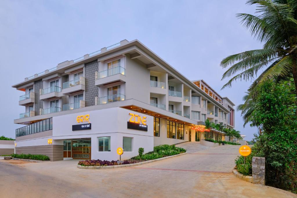 a large white building with a palm tree in front of it at Zone By The Park Gopalpur in Gopālpur