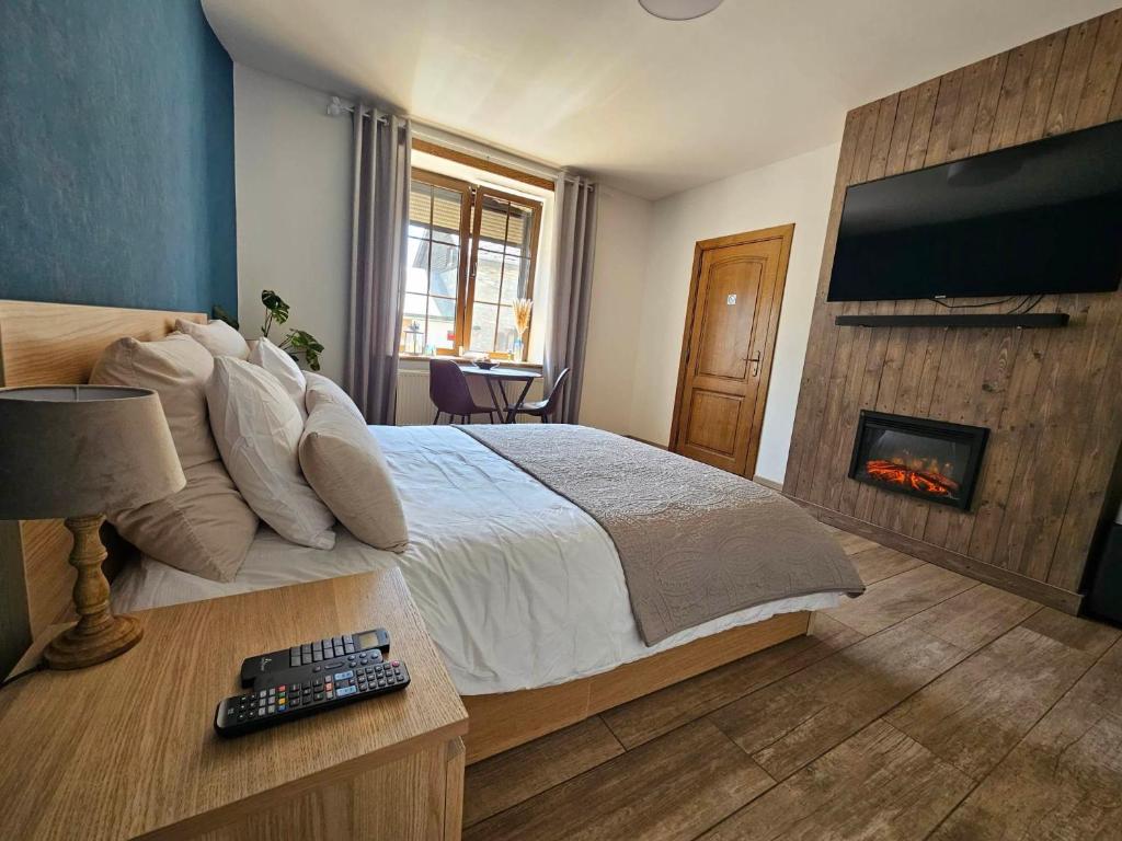 a bedroom with a bed with a fireplace and a television at Ferme La Joye in Houffalize