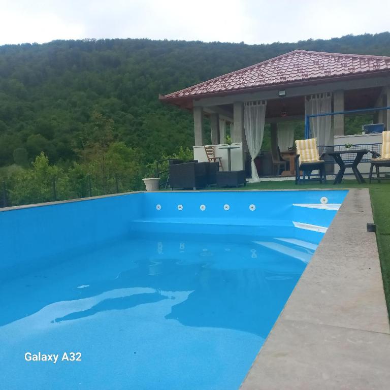 a blue swimming pool in front of a house at Kuća za odmor Lohovo in Bihać
