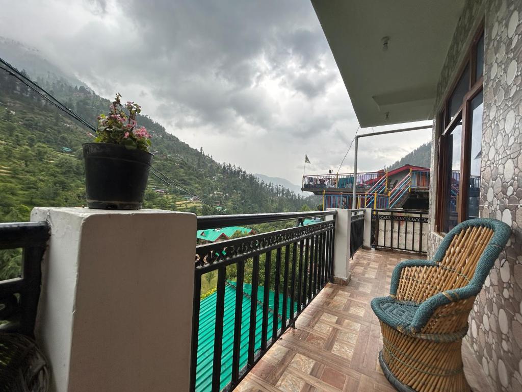 a balcony with two chairs and a view of a mountain at Peppy Nomads Apartment in Jibhi