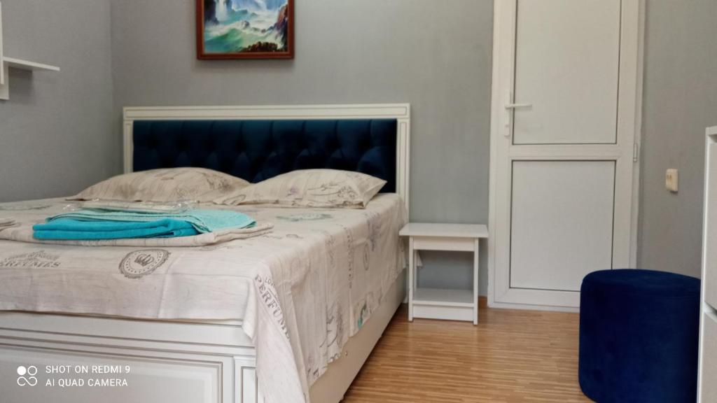 a bedroom with a white bed with a blue headboard at Samira in Gagra