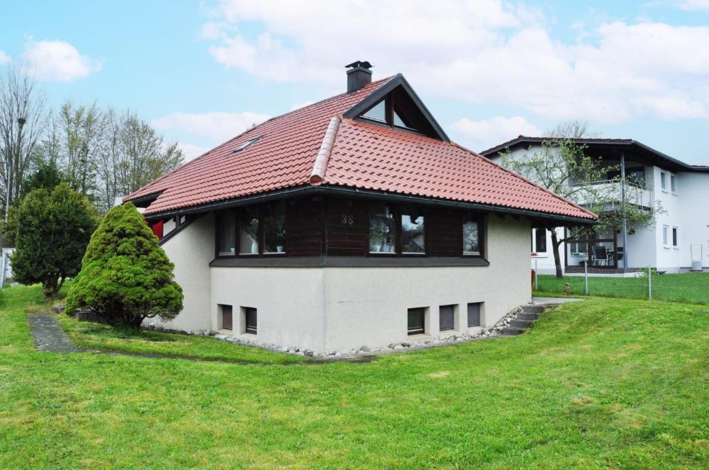 dom z czerwonym dachem na zielonym polu w obiekcie Haus Uhlennest w mieście Ühlingen-Birkendorf