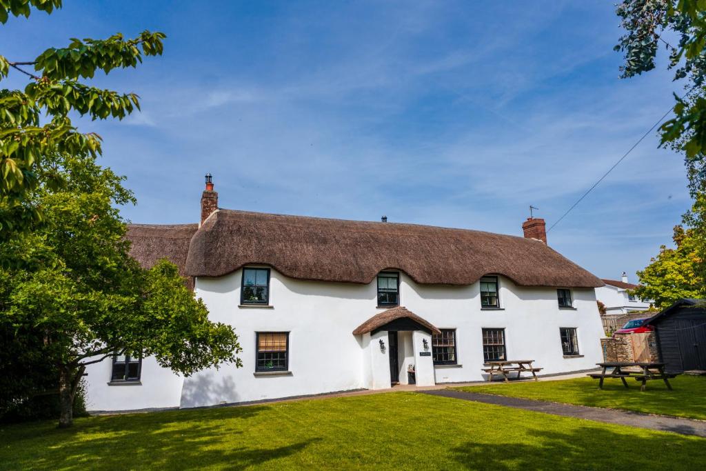 a large white house with a thatched roof at Poyers Farmhouse in Wrafton