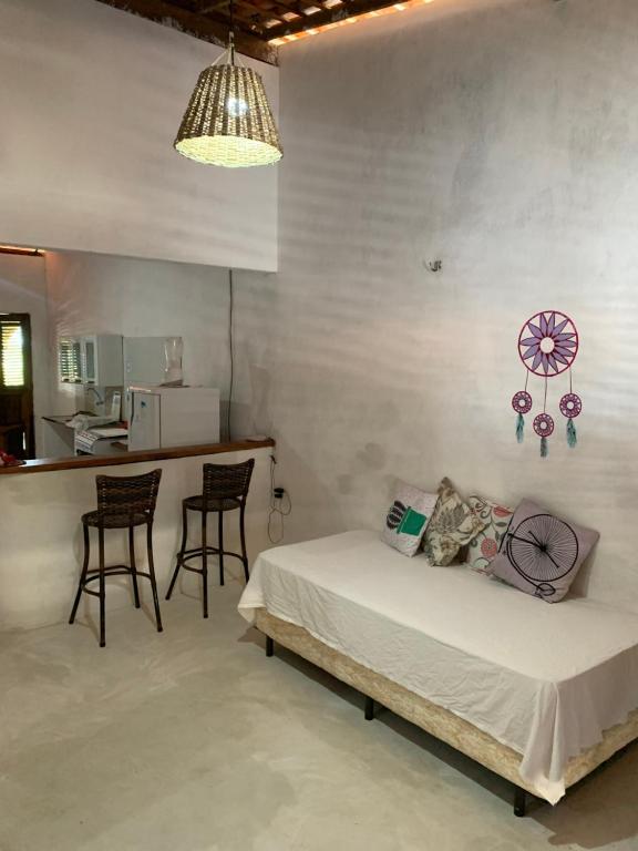 a bedroom with a bed and chairs and a kitchen at Casa Branca in Atins