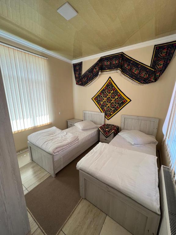 dwa łóżka w pokoju z dwoma oknami w obiekcie KHAN APARTMENTS w Samarkandzie