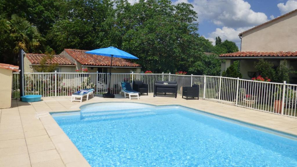 a swimming pool with a blue umbrella and chairs at Les Deux Riviéres in Les Touches-de-Périgny