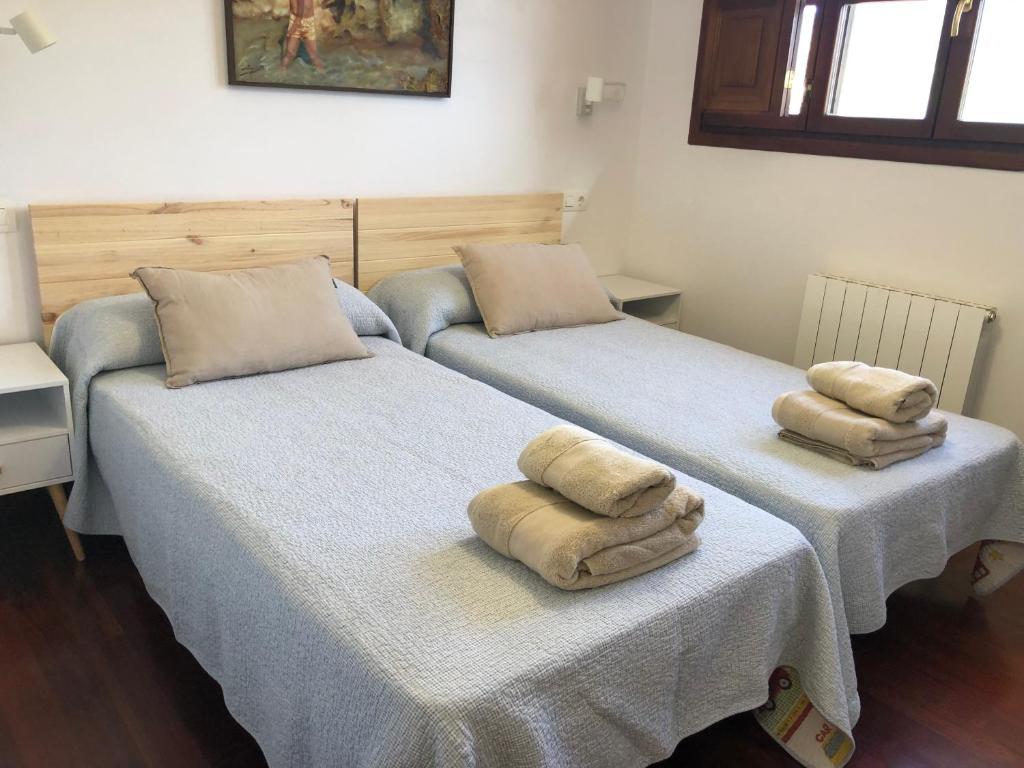 two beds with towels on top of them in a room at Casa Mojapies in Ribadesella