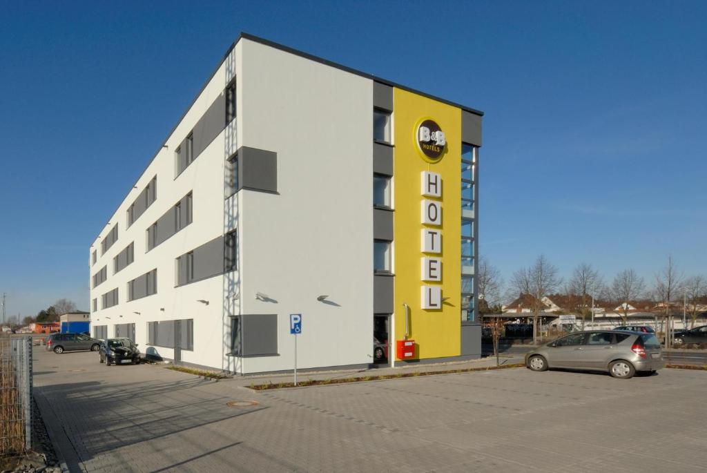 un gran edificio blanco y amarillo con aparcamiento en B&B Hotel Paderborn, en Paderborn