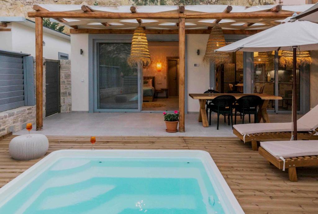 a swimming pool on a patio with a table and an umbrella at The Cave Villa in Matala