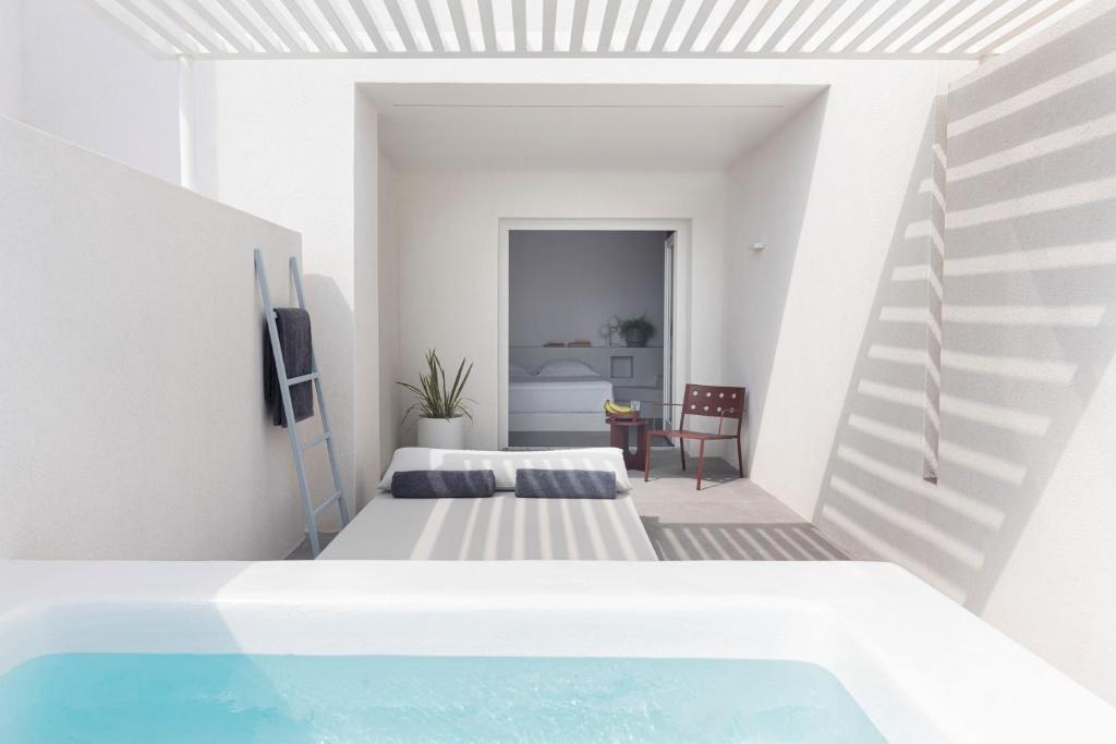 a white room with two beds and a swimming pool at Neo Suites in Fira