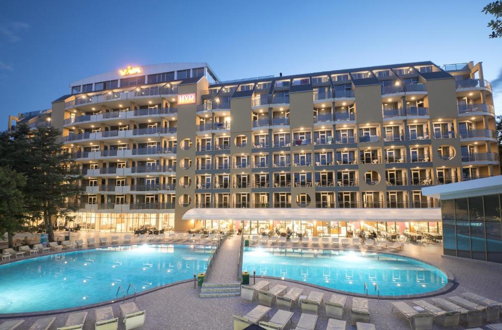 un hotel con una grande piscina e sedie di HVD Viva Club Ultra All Inclusive & Beach Snack Bar - Free Parking a Golden Sands