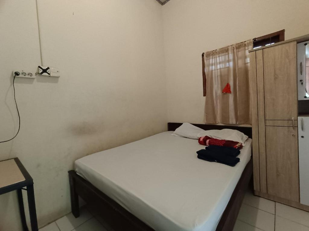 um pequeno quarto com uma cama branca e um armário em OYO 92591 Wisma Pangestu Syariah em Ujungtanjung