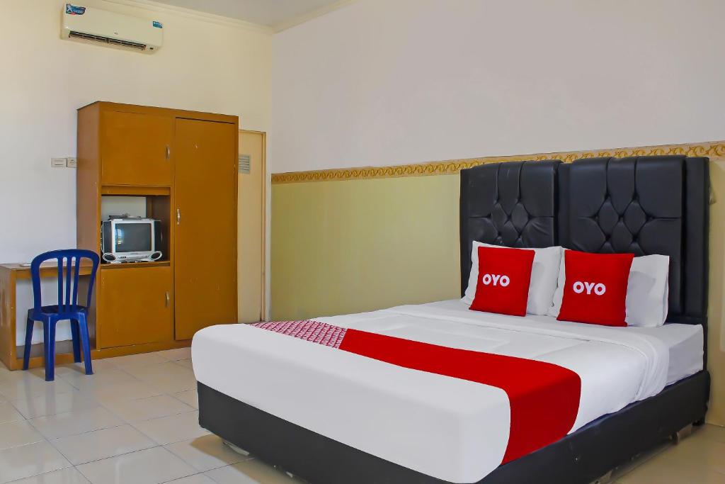 - une chambre avec un grand lit et des oreillers rouges dans l'établissement OYO 92593 Penginapan Sultan Haji 1, à Bandar Lampung