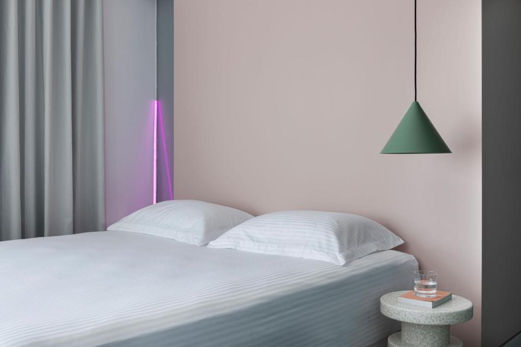 a bedroom with a white bed with a lamp and a table at Neo Suites in Fira