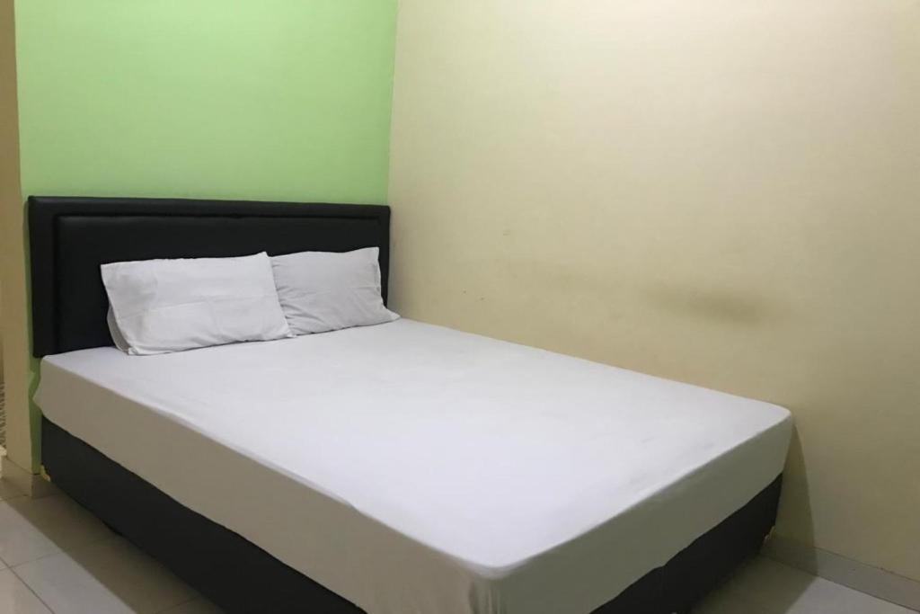 Cama blanca con cabecero negro y almohadas blancas en OYO 92608 Penginapan Mc Lodge, en Labuan Bajo