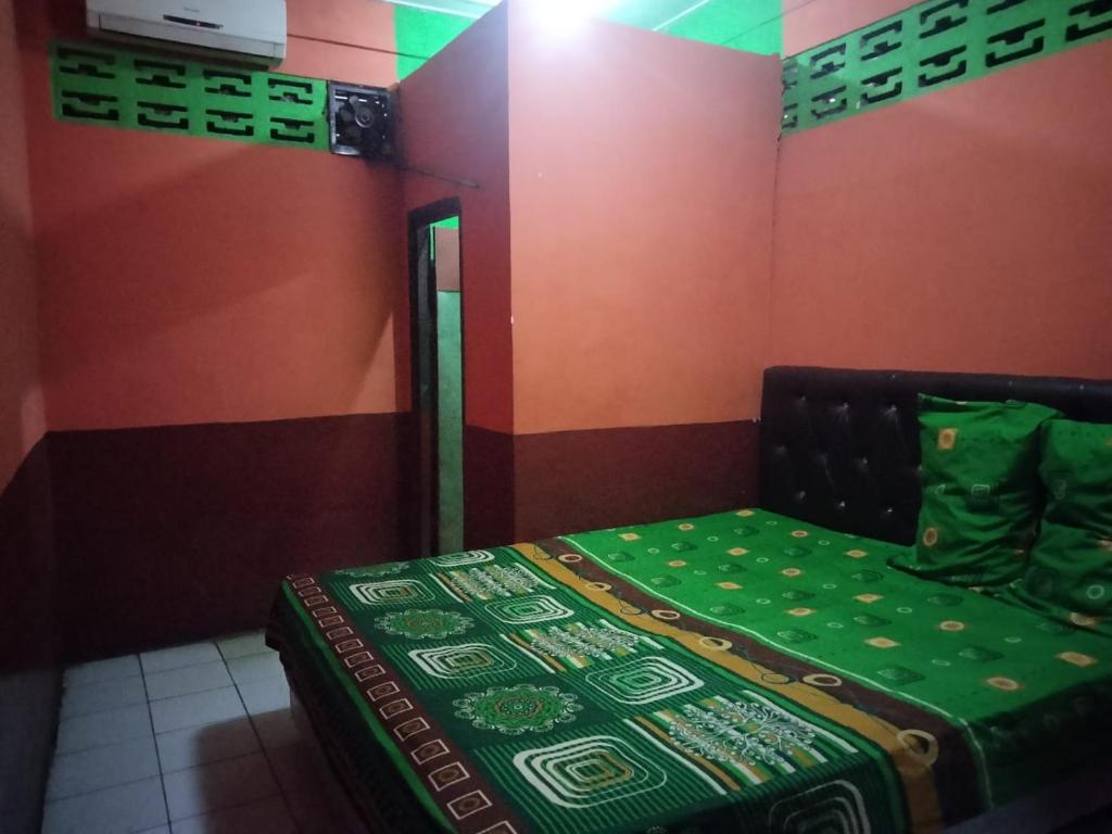 um pequeno quarto com uma cama com um cobertor verde em SPOT ON 92601 Penginapan Keluarga em Medan