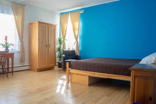 a bedroom with a bed and a blue wall at La Secousse in La Malbaie
