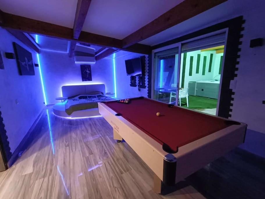 ein Zimmer mit einem Billardtisch in einem Zimmer mit lila Lichtern in der Unterkunft Appartement Le Secret Spa billard sensualité in Espondeilhan