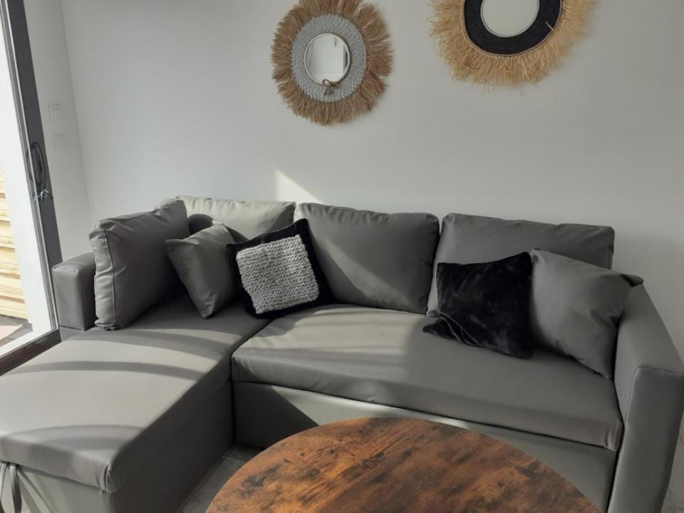 a gray couch with pillows and a table in a living room at Studio avec mezzanine in Gujan-Mestras