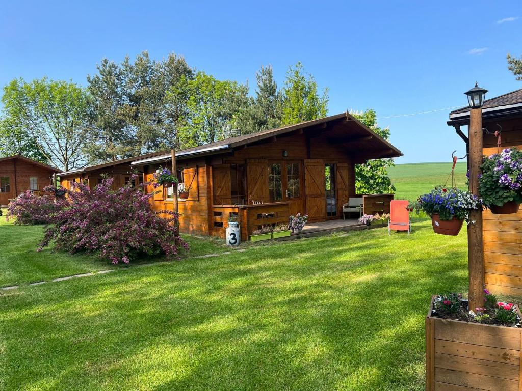 a large wooden cabin with a grass yard at Domki Radków in Wünschelburg