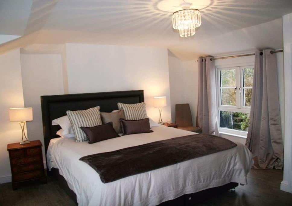 a bedroom with a large bed and a chandelier at Sommersway Cottage in Torquay