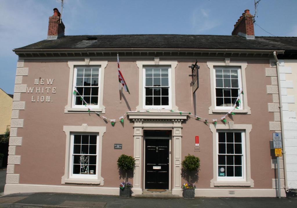 una casa rosa con un cartel que dice nuevo lote blanco en The New White Lion en Llandovery