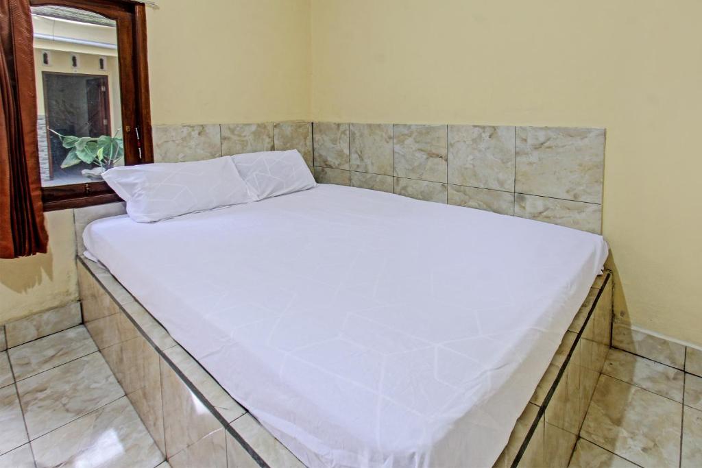 een groot wit bed in een kamer met een raam bij OYO 92619 Inn Homestay in Lombok