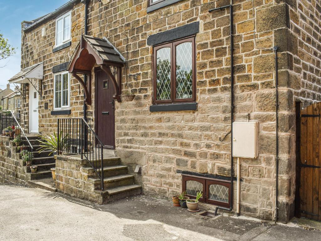 a brick building with a brown door and stairs at Weavers Cottage in Barnsley