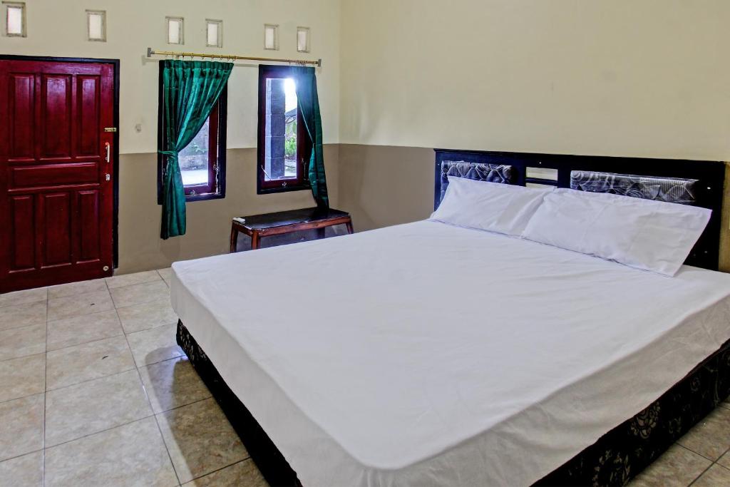 1 dormitorio con 1 cama blanca grande y puerta roja en OYO 92624 Stone Homestay, en Tjakranegara