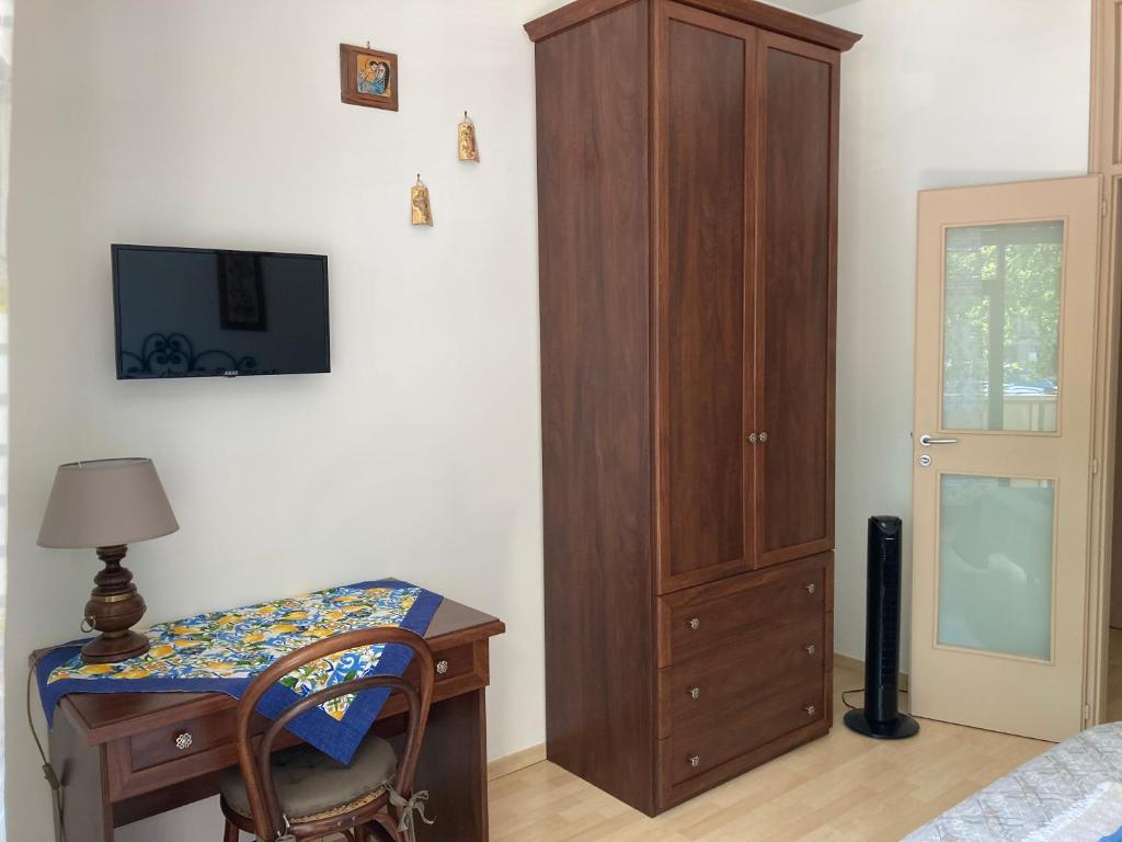 sypialnia z drewnianą szafką i biurkiem z lampką w obiekcie casa vacanza brezza di maestrale w mieście Salerno