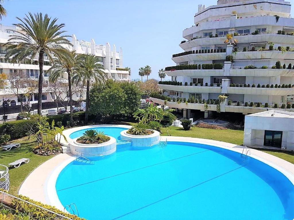 a large blue swimming pool in front of a large building at SUPERIOR 3 bedroom MARBELLA center close to beach in Marbella