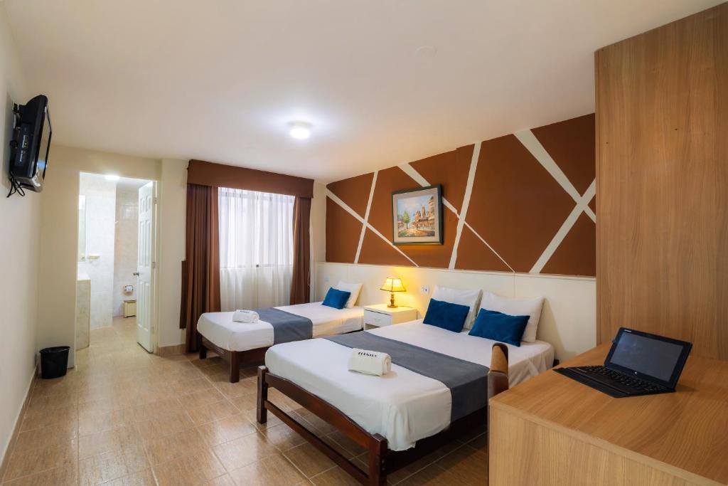 a hotel room with two beds and a laptop on a desk at Hotel Country Trujillo in Trujillo