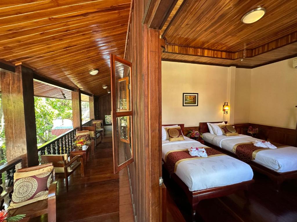 a bedroom with two beds and a balcony at Ammata Boutique Villa in Luang Prabang