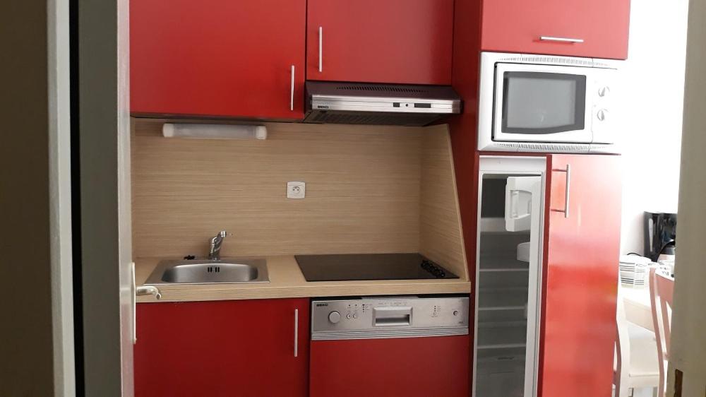 uma pequena cozinha com armários vermelhos e um lavatório em LE VALLON DU ROY em Sanary-sur-Mer