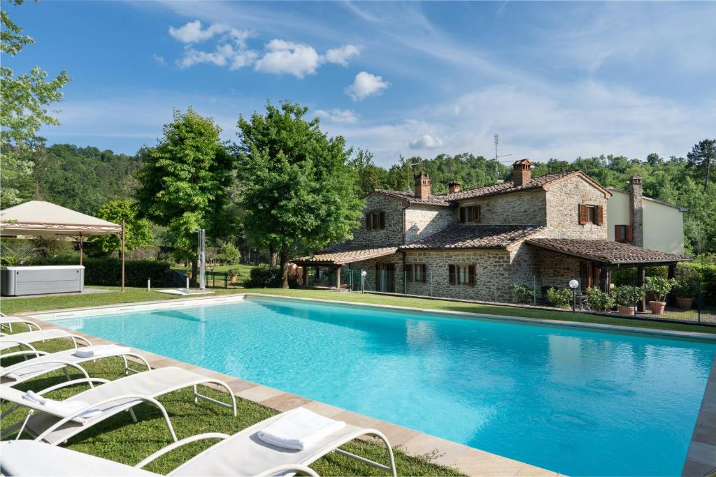 una piscina frente a una casa con tumbonas blancas en Villa Il Mulino, en Calbenzano