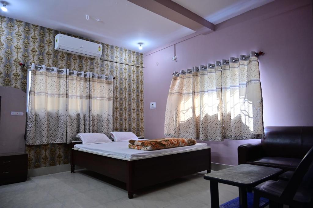 a bedroom with a bed and a chair and curtains at Hotel Palak in Deoghar