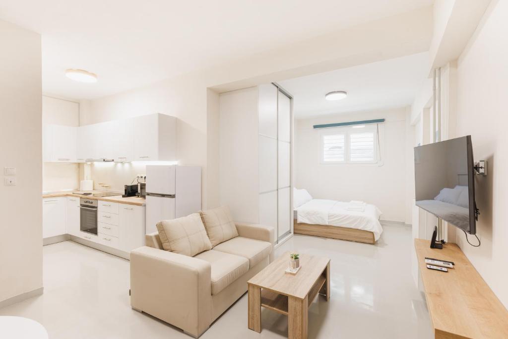 アテネにあるFully renovated luxurious semi-basement studioの白いリビングルーム(ソファ、テーブル付)