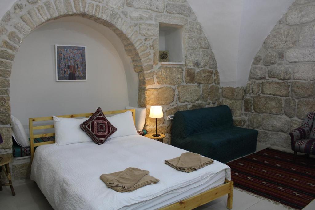 ein Schlafzimmer mit einem Bett und einem blauen Stuhl in der Unterkunft Dar As-Sideh pilgrim house in Bethlehem