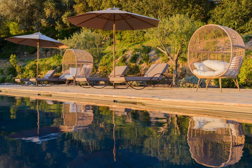un grupo de sillas y sombrillas junto a una piscina en Terre de Maquis, maison d'hôtes vue mer Corse, en Sari-dʼOrcino