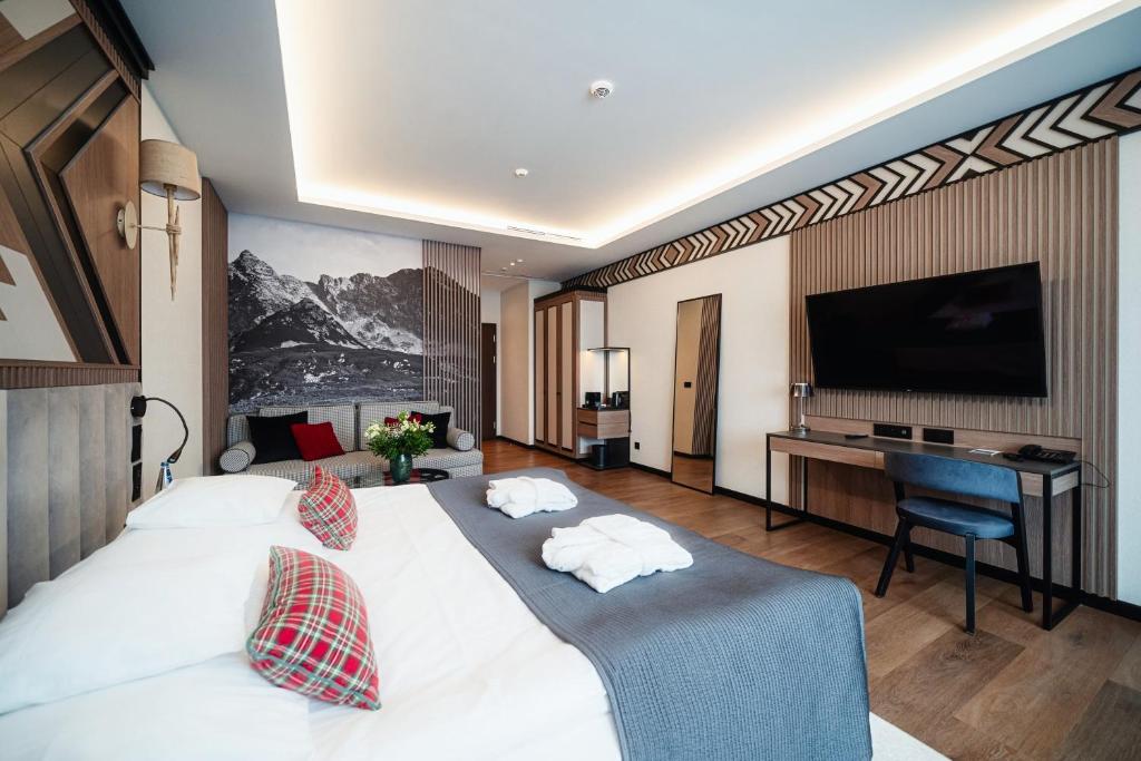 ein Hotelzimmer mit einem großen weißen Bett und einem Schreibtisch in der Unterkunft Rysy Boutique Hotel in Zakopane