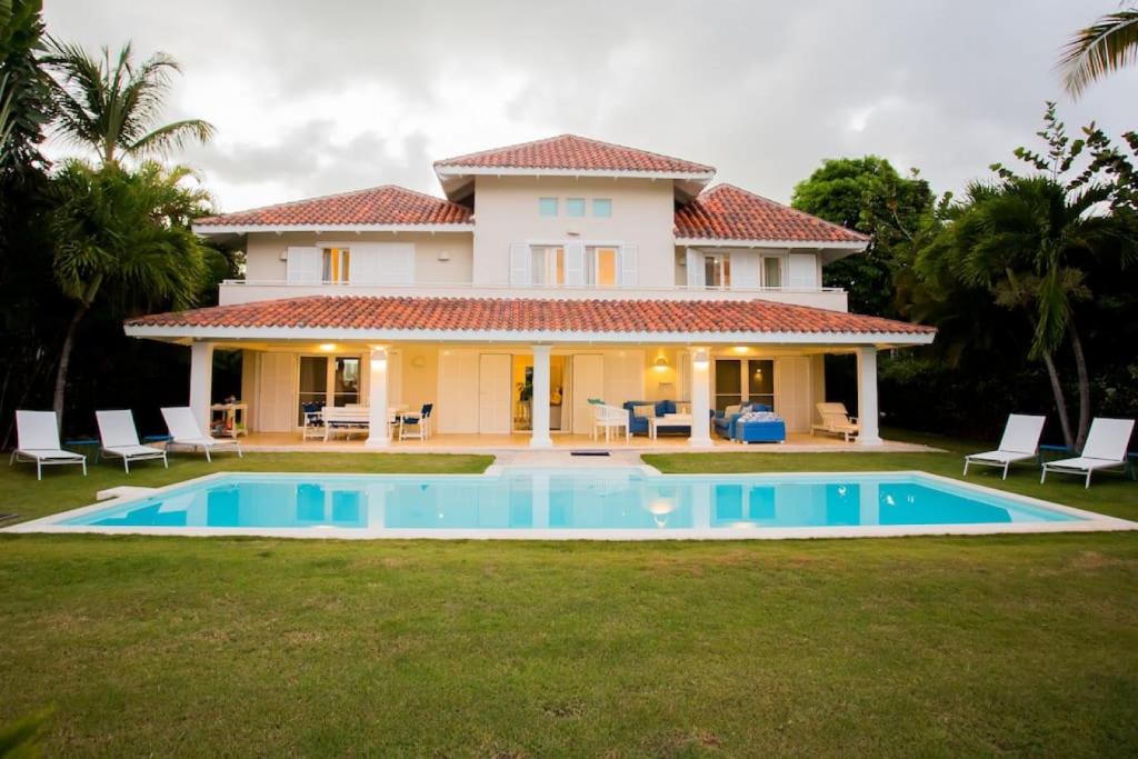 a villa with a swimming pool in front of a house at TORTUGA B7 GOLF FRONT VILLA WITH POOL CART AND MAiD in Punta Cana
