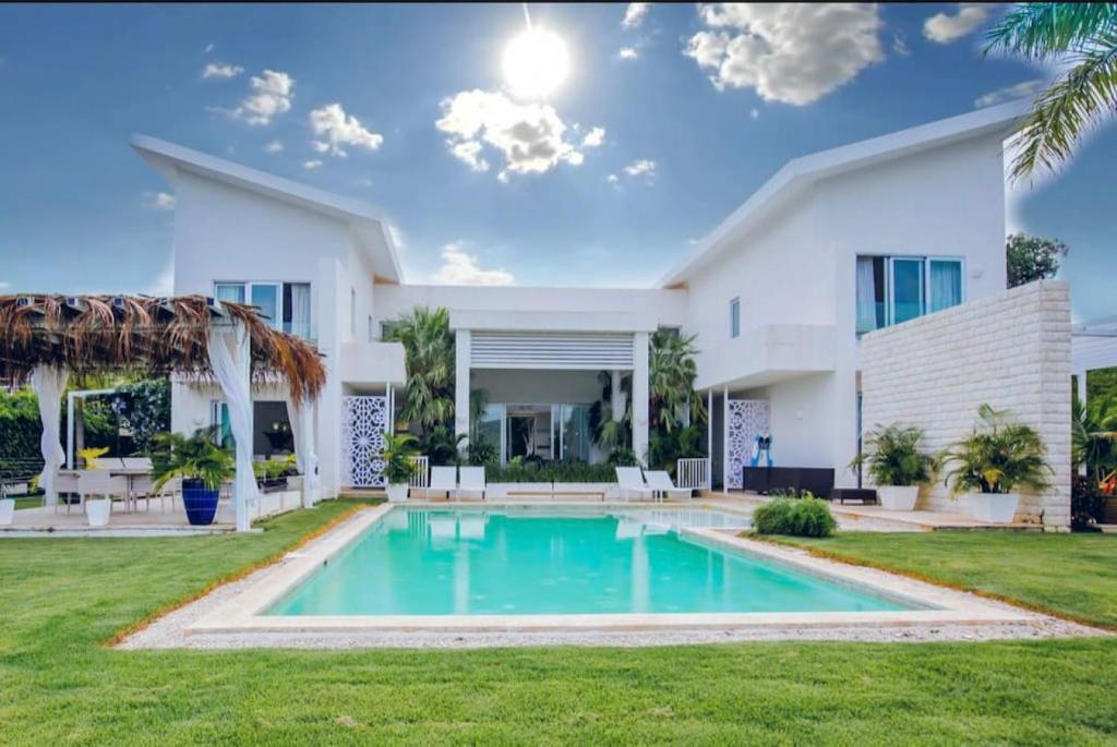 ein großes weißes Haus mit einem Pool im Hof in der Unterkunft Hacienda 51 5BR lakefront villa with cook maid and golf cart in Punta Cana