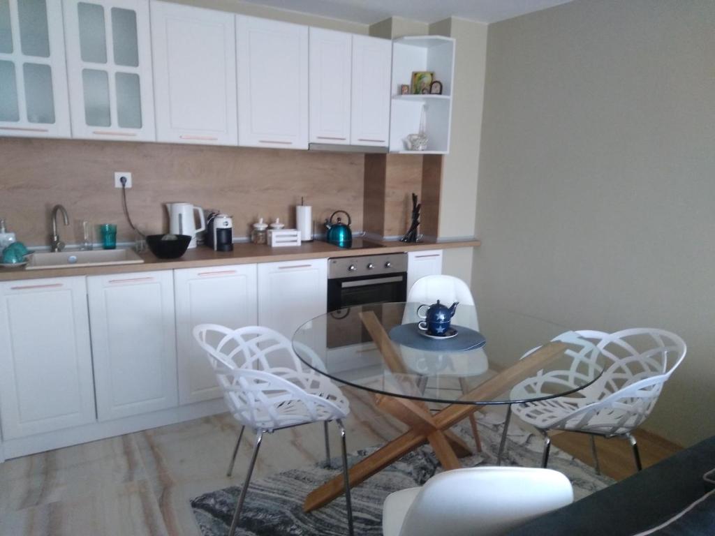 a kitchen with white cabinets and a glass table and chairs at Апартамент Яница in Razlog