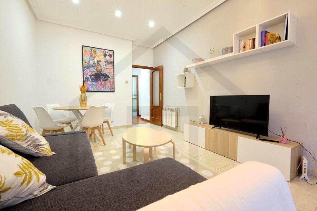 ein Wohnzimmer mit einem Sofa, einem TV und einem Tisch in der Unterkunft La casa de Begoña - a un paso del centro de Gijón. in Gijón