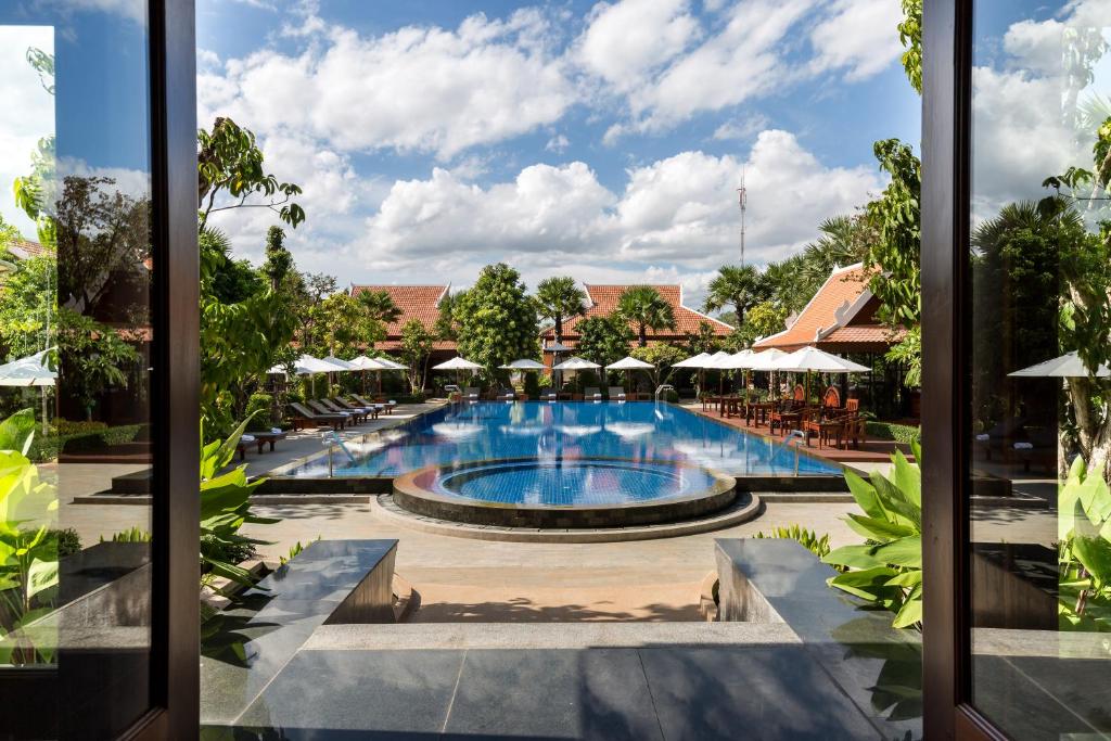 vista para uma piscina num resort com mesas e guarda-sóis em Angkor Privilege Resort & Spa em Siem Reap