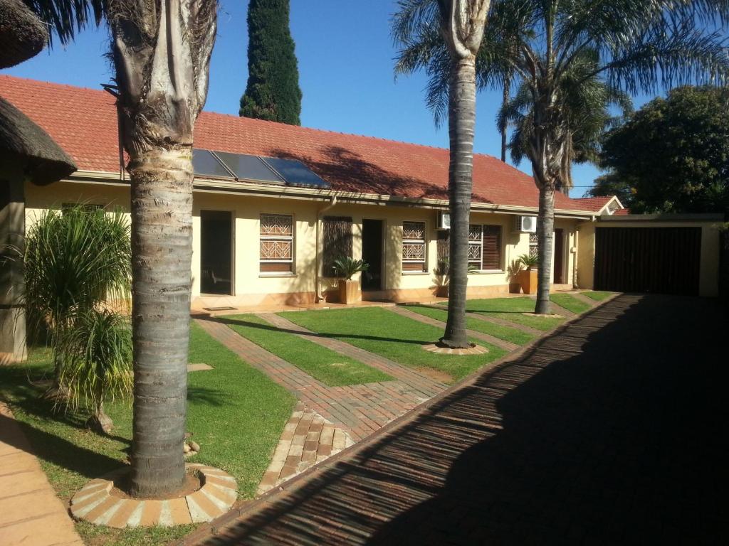 a house with palm trees in front of it at Big "5" Guesthouse in Kempton Park