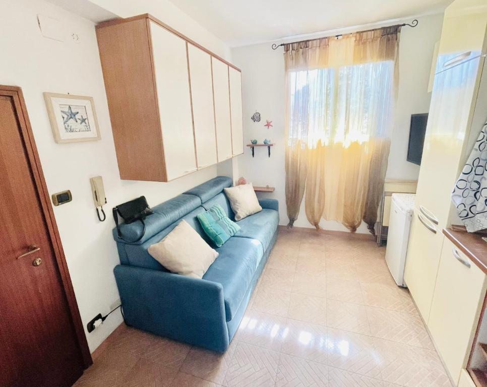 ein Wohnzimmer mit einem blauen Sofa und einem Fenster in der Unterkunft Petit in Porto Ercole