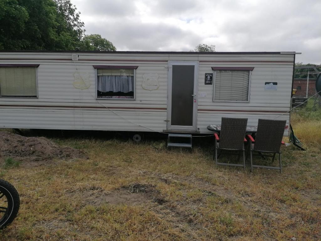 a white caravan parked in a field with two chairs at Mobilheim in Alttrebbin in Neutrebbin